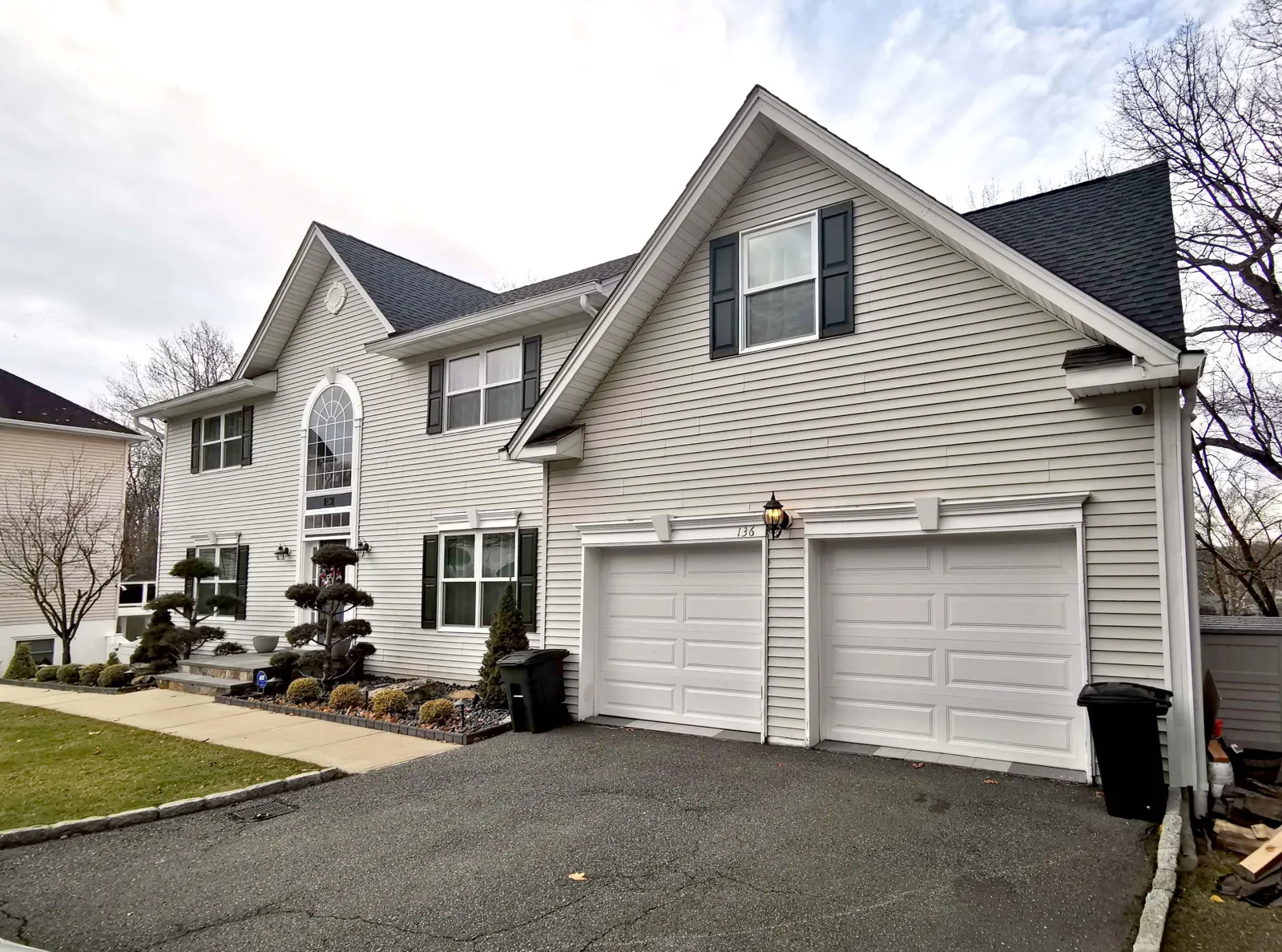 Patrick Avenue — Entry and garage wing — angled view showing the new stone columns, black trim, and flush wood garage doors — before